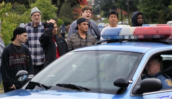Neighbors look on at the scene of a shooting that left four people dead and another wounded Thursday in Seattle. The woman suspected of firing the shots at the southwest Seattle home apparently is among the dead.